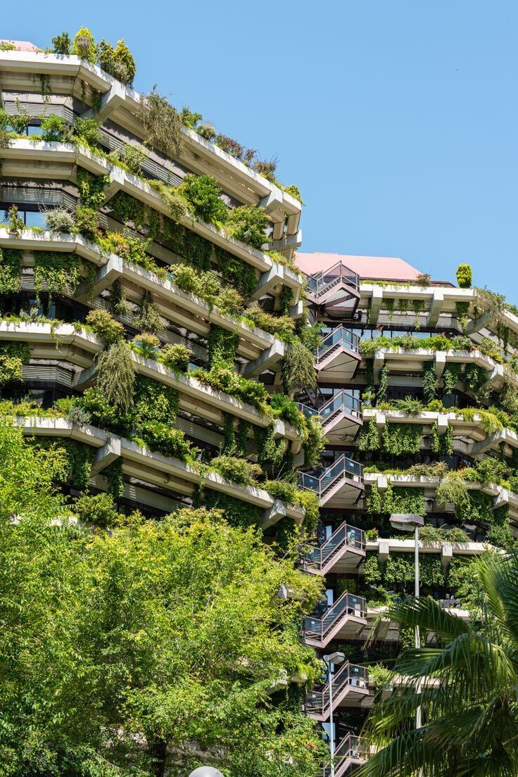 A tall building densely covered in green plants, symbolizing regenerative design
