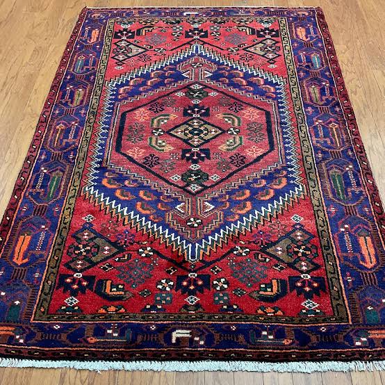 Rolled red and blue patterned area rug